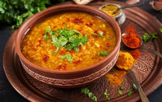 Traditional Indian soup lentils. Indian Dhal spicy curry in bowl, spices, herbs, rustic black wooden background. Authentic Indian dish.